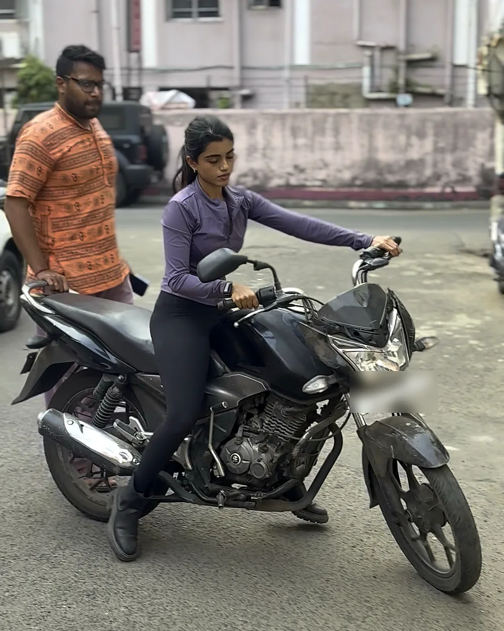 Woman learning clutch control on a motorcycle with her trainer