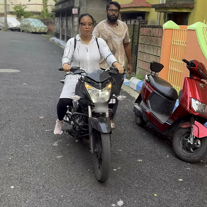 Woman riding a motorcycle with her trainer following