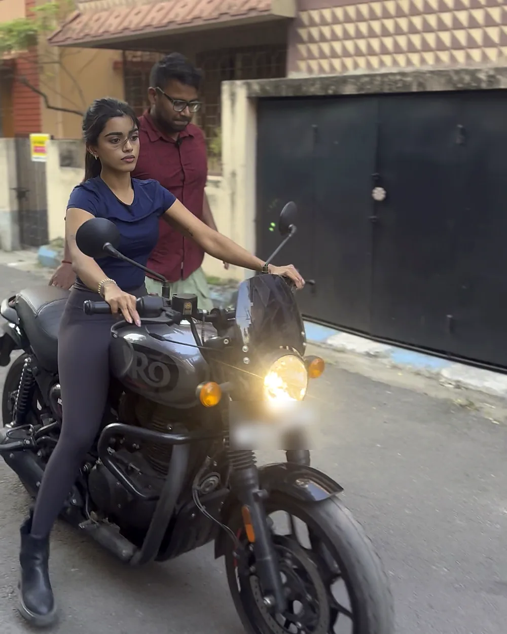 Learner riding a motorcycle with her trainer beside her