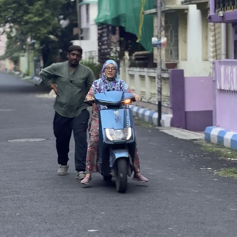 Trainer walking beside a learner on a quiet lane before road practice