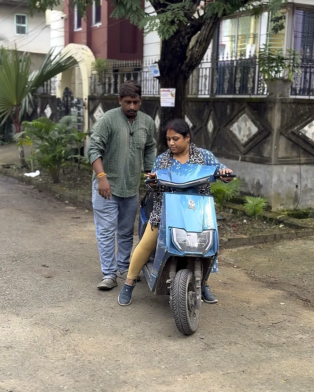 Trainer guiding a beginner on a scooty in a quiet Tollygunge lane