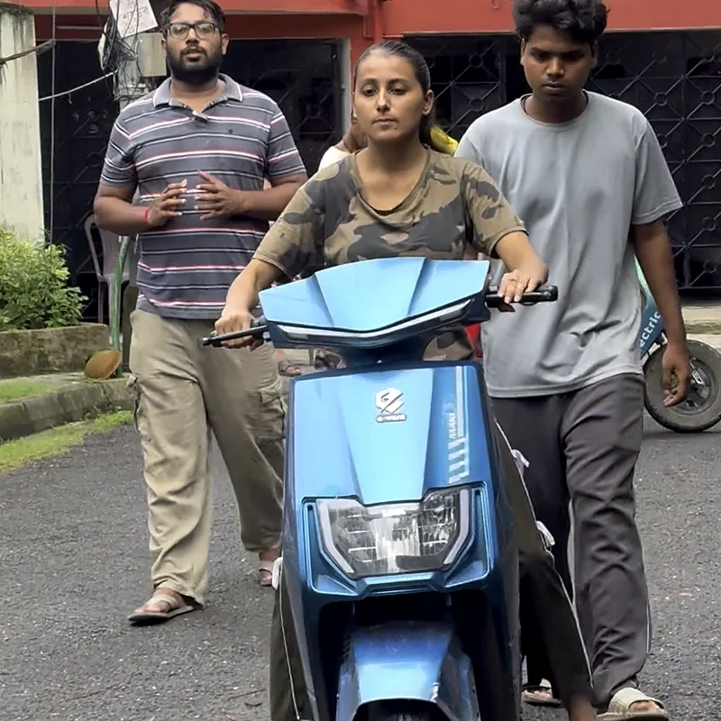 Two trainers walking beside a beginner on her first scooty ride